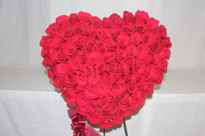 Heart-shaped bouquet of red roses with a ribbon at the base