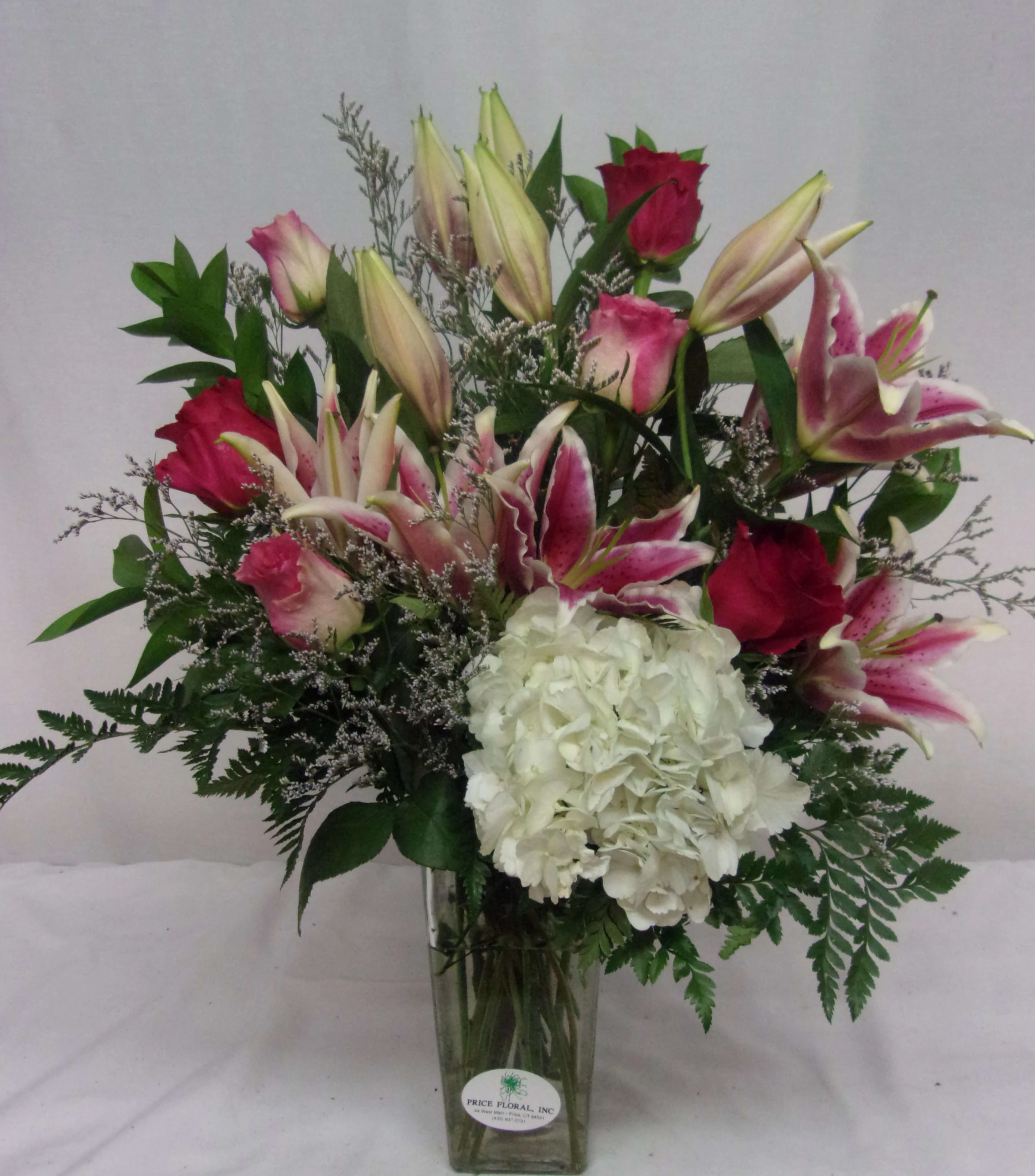 Pink lilies and roses with white hydrangea in a glass vase