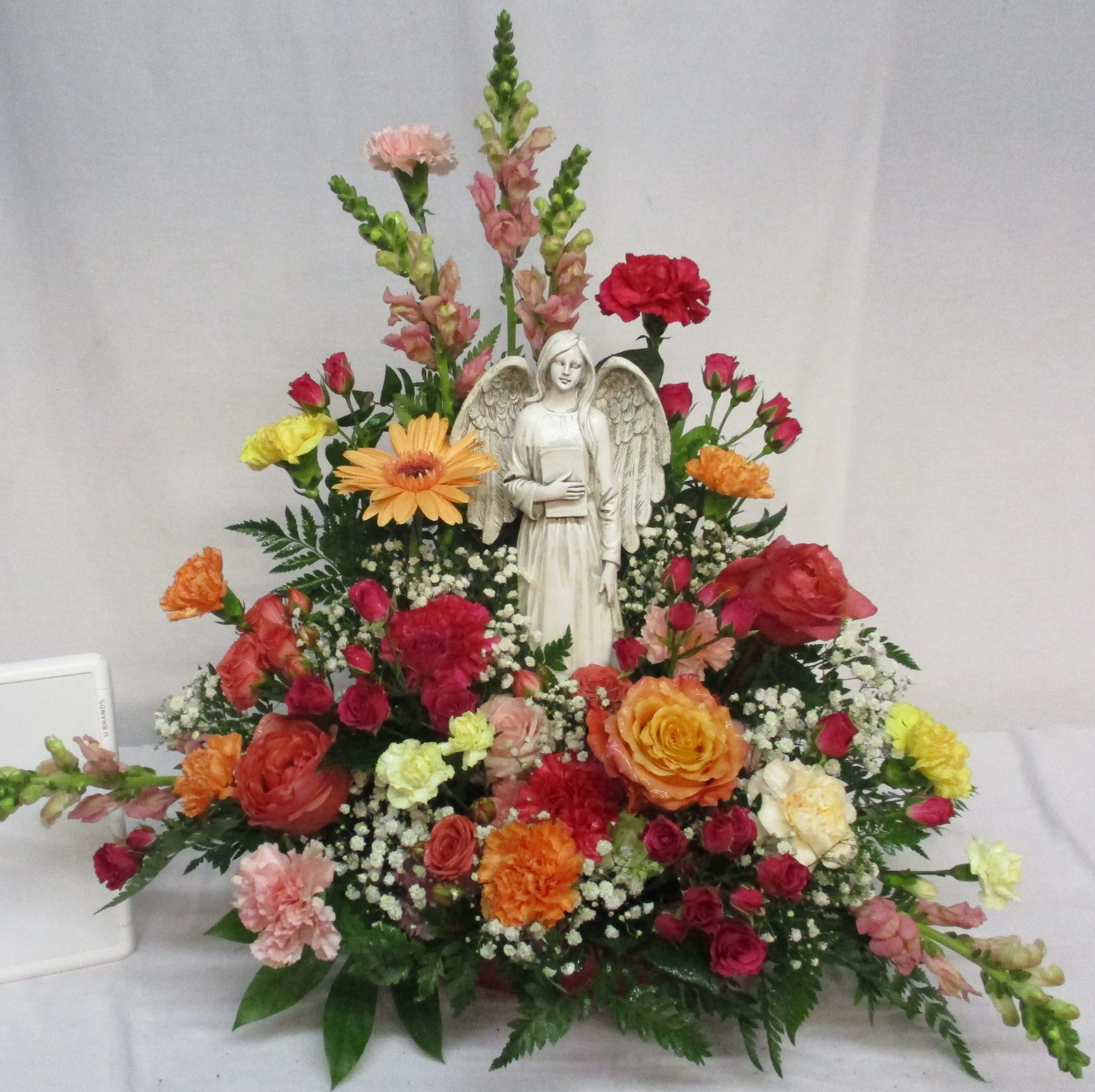 Mixed floral arrangement with an angel statue centerpiece