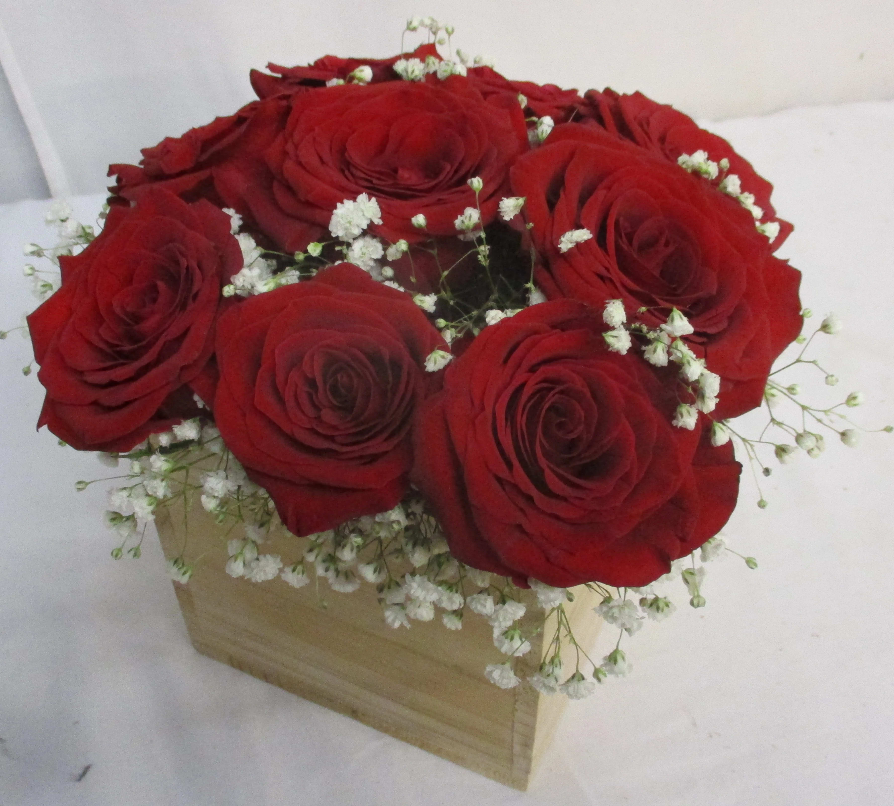Red roses arranged in a wooden box with white baby's breath