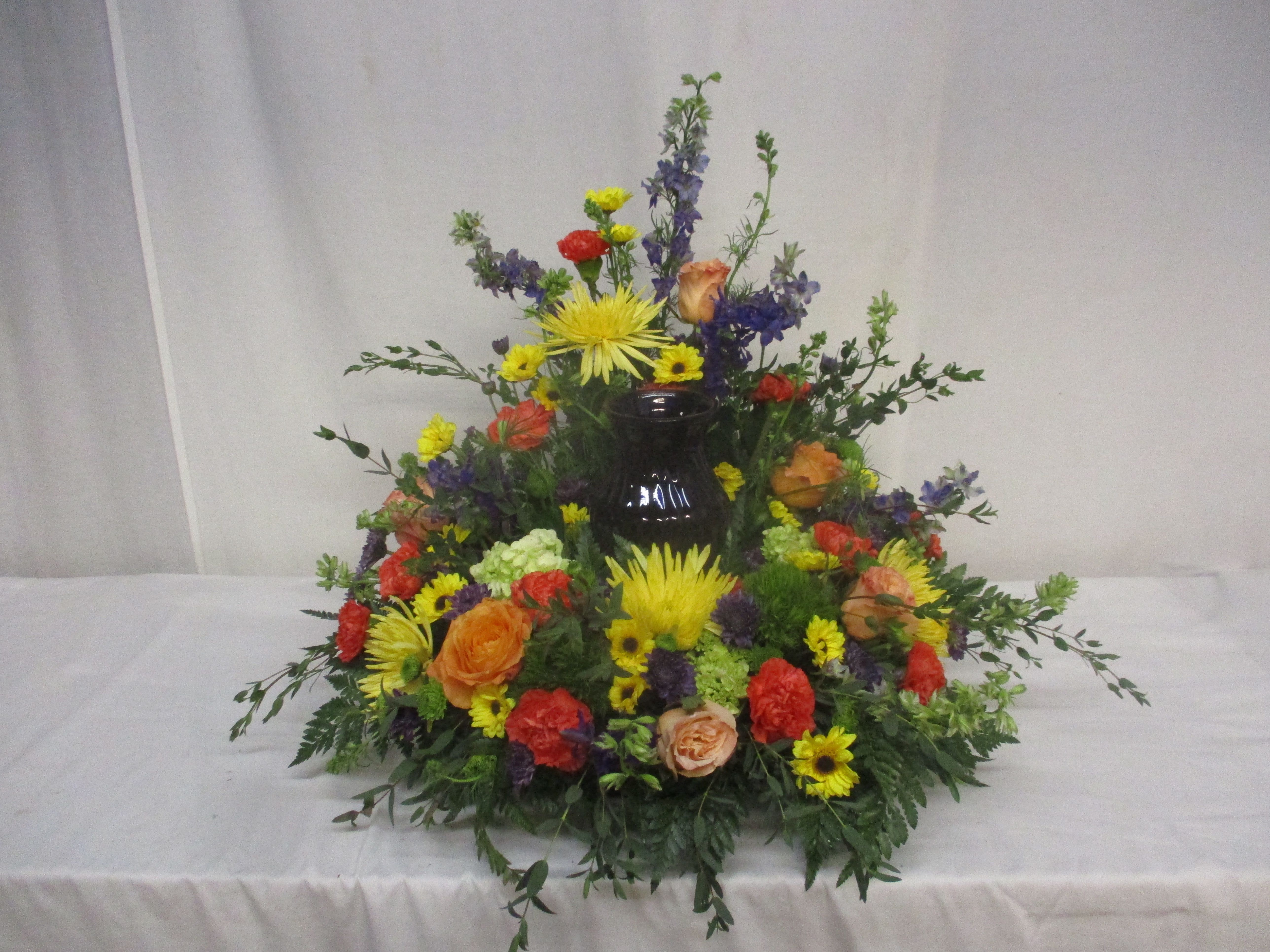 Colorful floral arrangement around a dark vase centerpiece