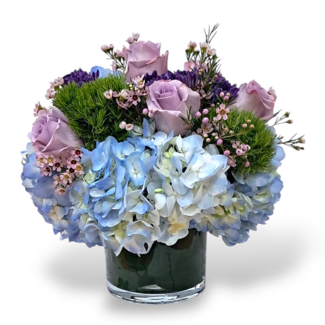 Lavender roses and blue hydrangeas in a glass vase