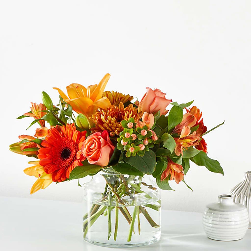 Orange and peach mixed bouquet in a clear glass vase
