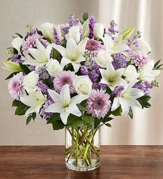 Sincerest Sorrow  Lavender &amp; White - Let a deeply heartfelt sentiment be delivered in true form. Our lush, bountiful bouquet of lavender and white blooms features an elegant mix of roses, lilies and cremones, hand-designed inside a classic clear glass vase. When sent to a service or to the home of family or friends, it makes a genuinely heartwarming gesture.