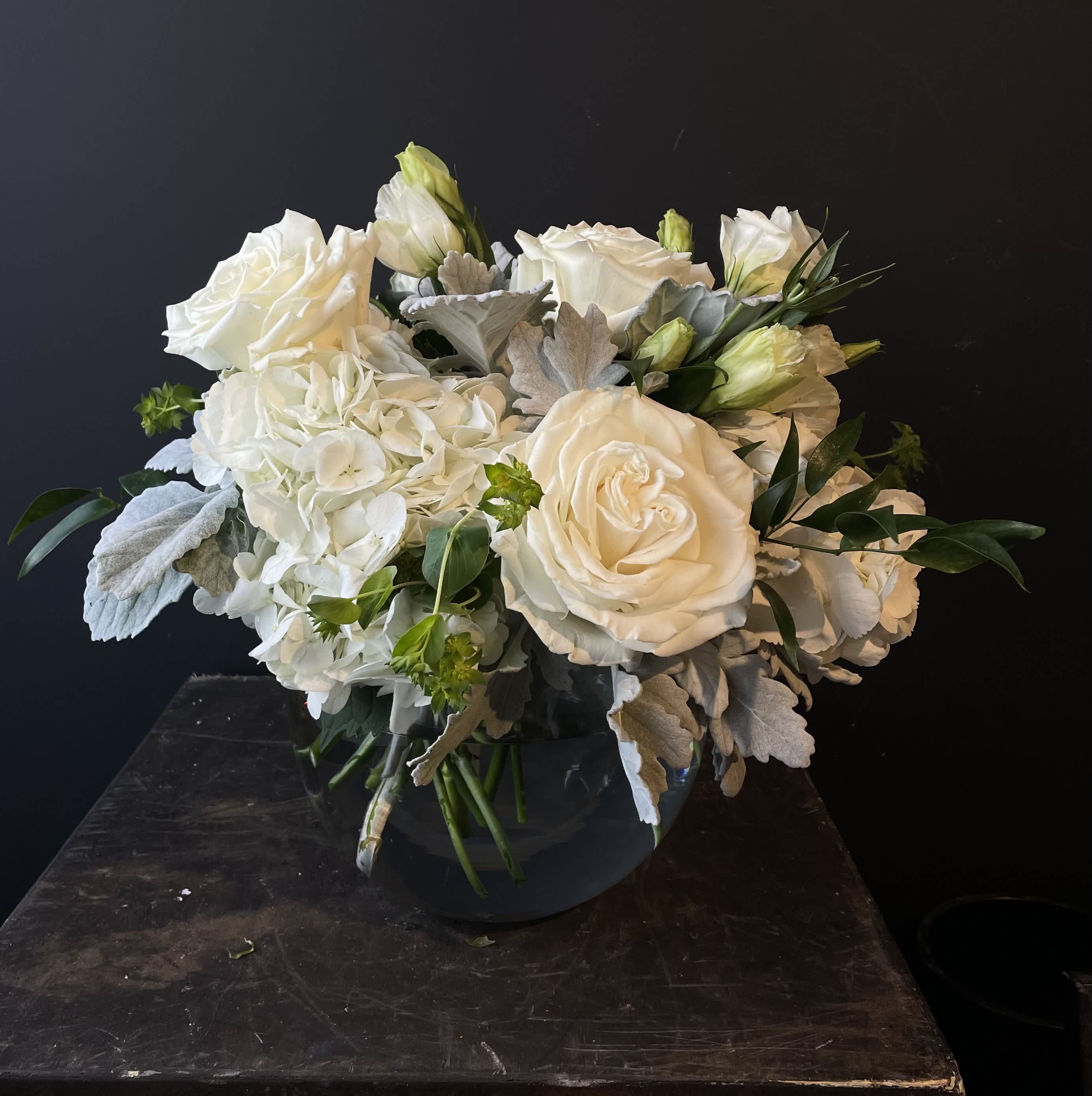 White roses and hydrangeas arranged in a dark vase