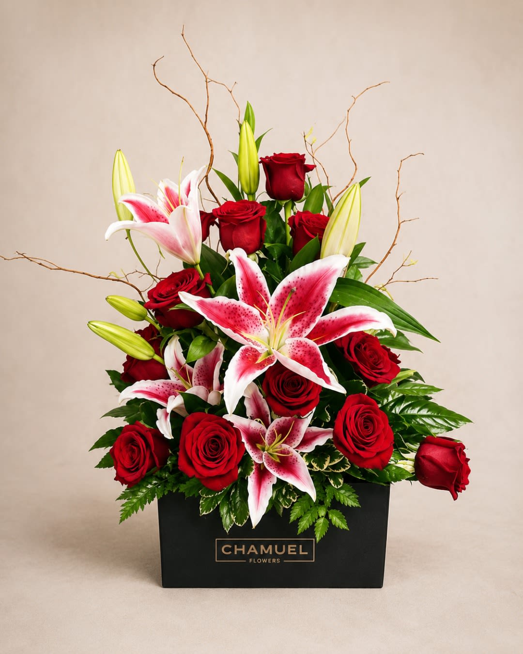 RENAISSANCE VASE ARRANGEMENT RED ROSSES - Velvety red roses meet pink-and-white stargazer lilies in a compact, modern gift-box arrangement designed to make someone feel truly cherished. This flower arrangement and anniversary bouquet arrives in a sleek black rectangular box with tall decorative twigs that add sculptural height and a dramatic silhouette-perfect for birthdays, Valentine's Day, Mother's Day, or a bold "thinking of you" surprise around Memorial Day or any heartfelt moment.  Densely layered blooms include open roses and lilies with a few graceful lily buds for variation, creating rich red and soft pink-and-white contrast against fresh greenery. The presentation is polished and contemporary, sized to sit beautifully on a mantle, bedside table, or office desk. Order for same-day delivery when available to make the recipient feel celebrated; stems arrive arranged and ready to display with simple fresh-water care to extend bloom life.