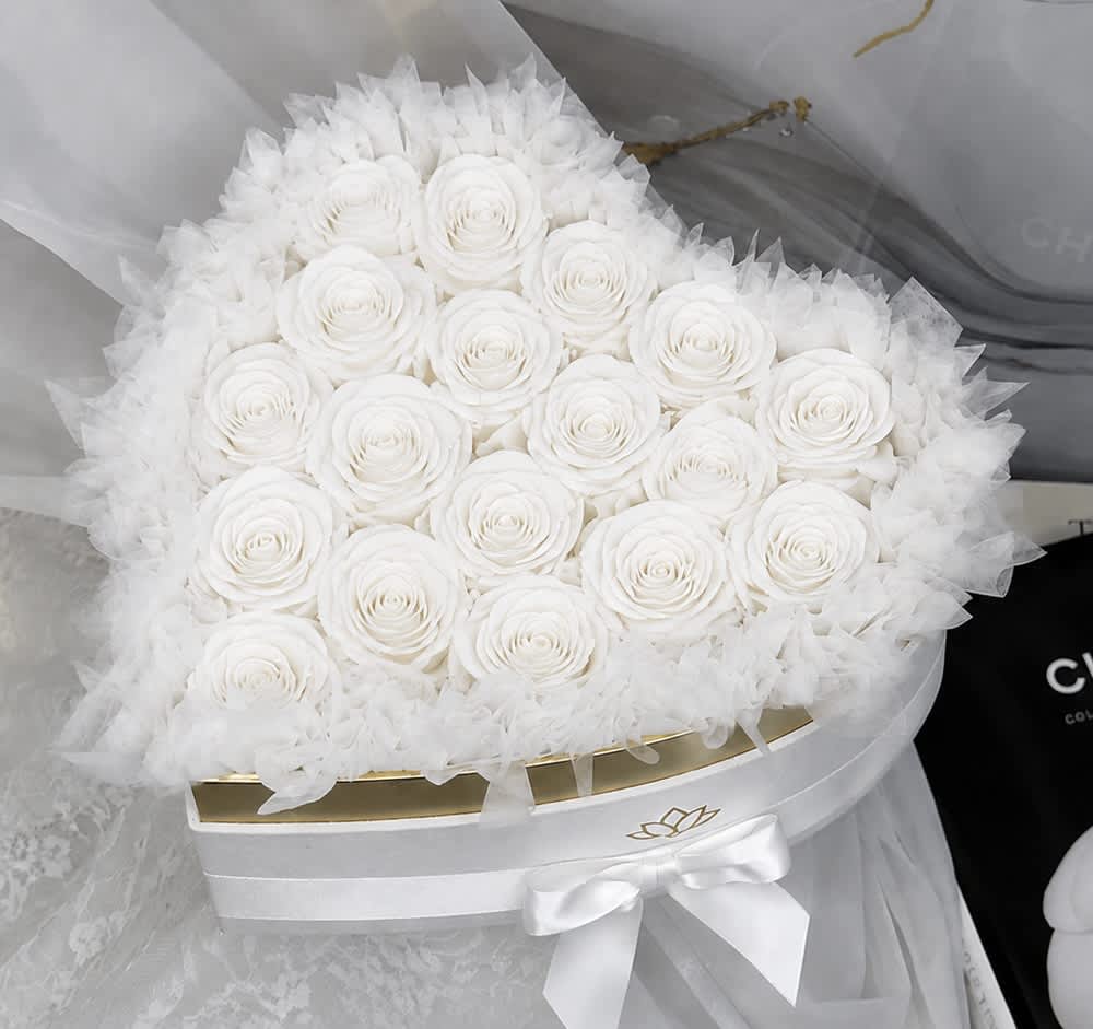 Round bouquet of white roses wrapped in sheer white tulle