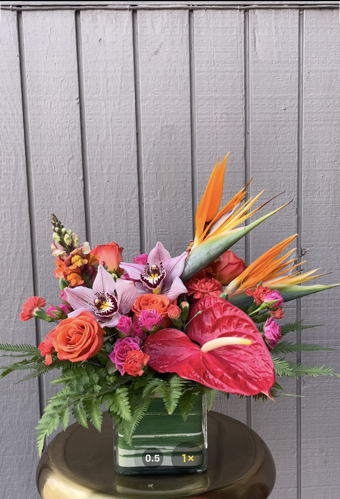Tropical bouquet with orchids, roses, anthurium, and bird of paradise in a glass vase