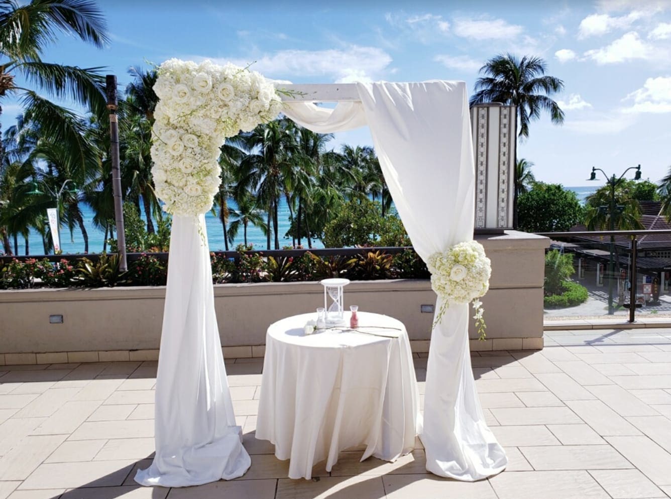 White floral wedding arch with draped fabric and a small round table