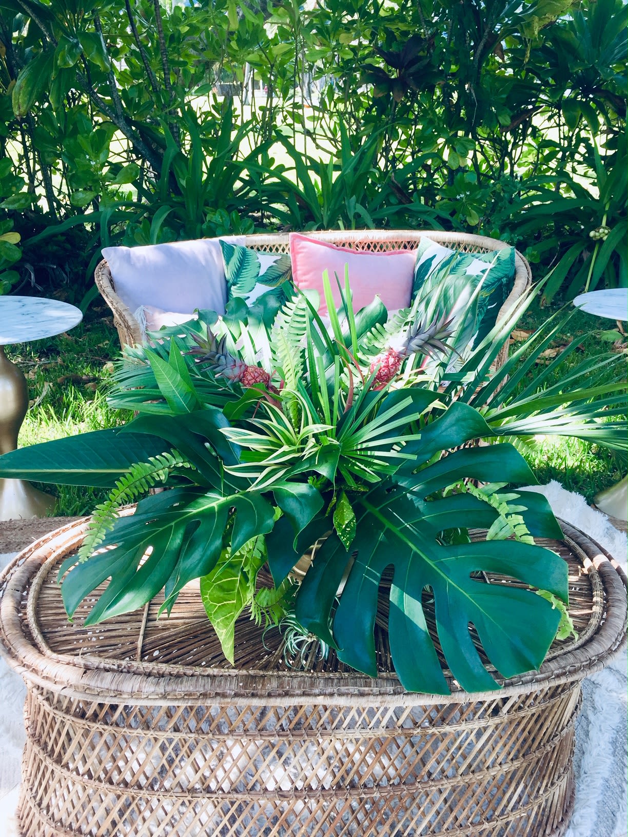 Tropical plant arrangement in a woven basket on a patio table