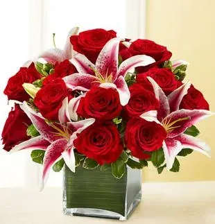Red roses and pink lilies arranged in a square glass vase
