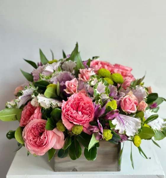 Pink roses and mixed blooms arranged in a wooden box