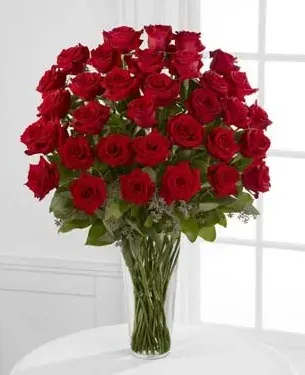 Tall bouquet of red roses in a clear glass vase