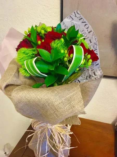 Bouquet of red roses wrapped in burlap with green ribbon