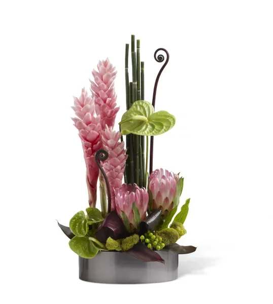 Pink tropical flowers in a low gray container with bamboo accents