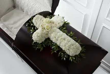 White floral cross arrangement on a dark casket