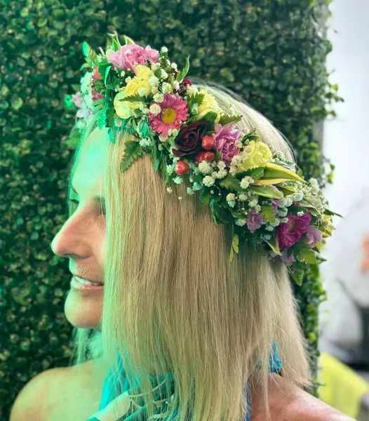 Woman wearing a floral crown with pink, yellow, and purple flowers