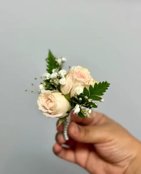 Small cream rose boutonniere with white filler flowers and greenery