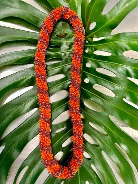 Orange flower lei on large split green leaves