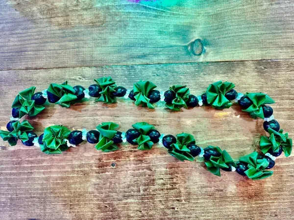 Green and dark blue beaded garland laid on a wooden surface