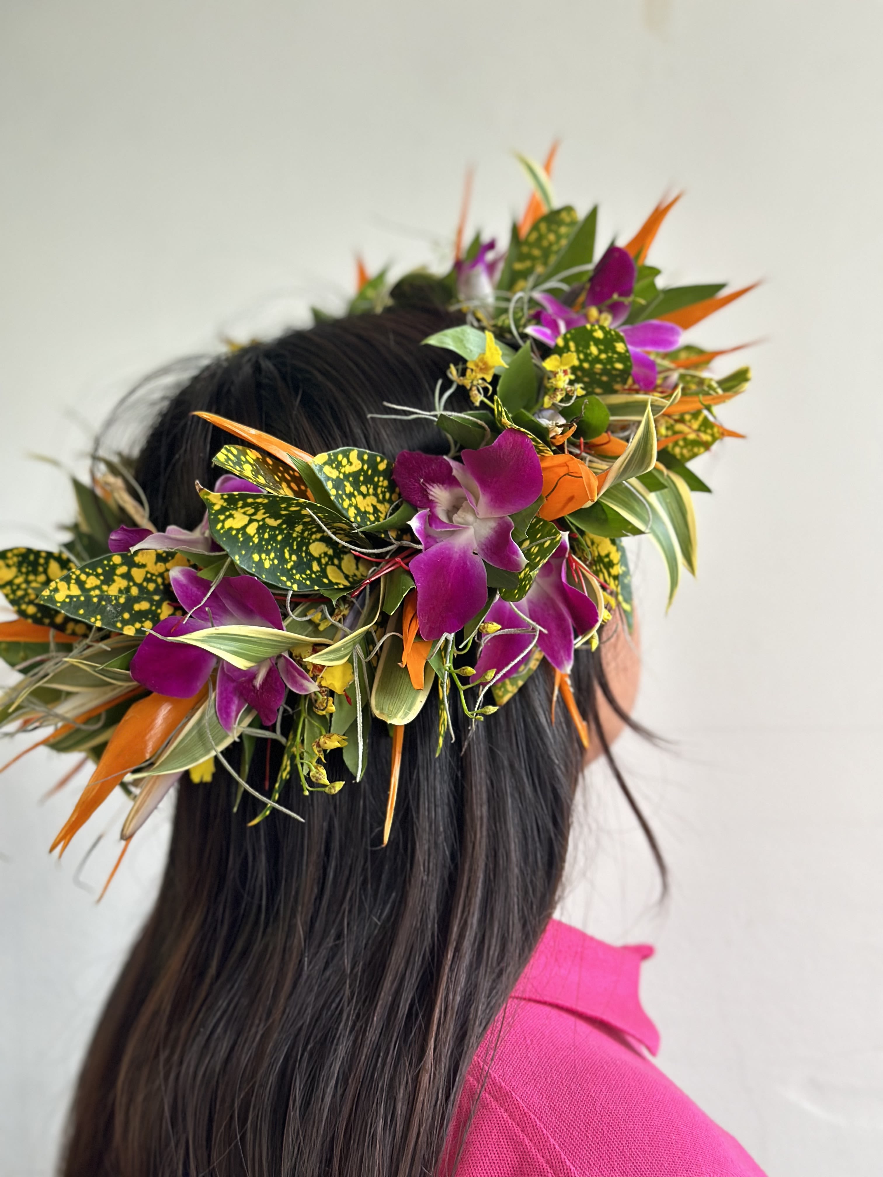 Tropical flower crown with purple orchids and orange accents on a person's head