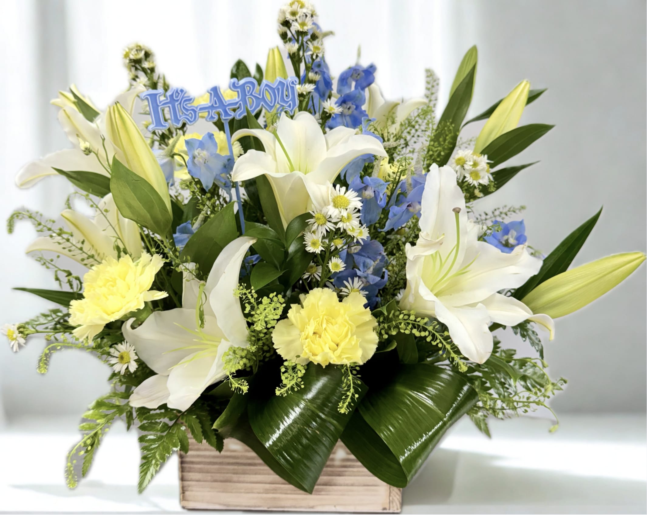 Blue and white floral arrangement with a "It's a Boy" sign in a wooden box