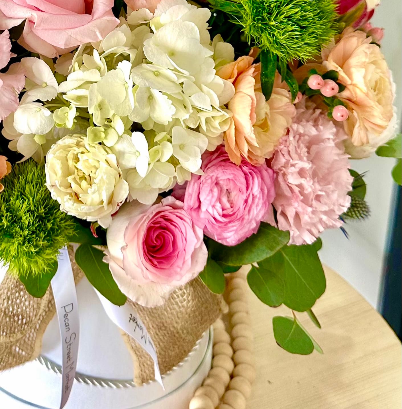 Pink and cream bouquet with roses, hydrangea, and carnations in a wrapped container