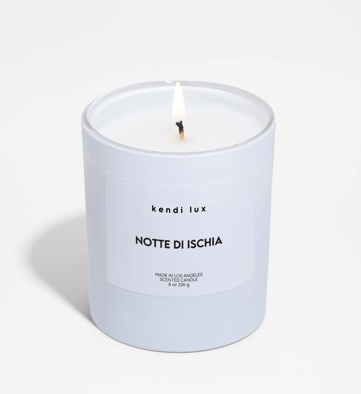 Lit white scented candle in a frosted glass jar