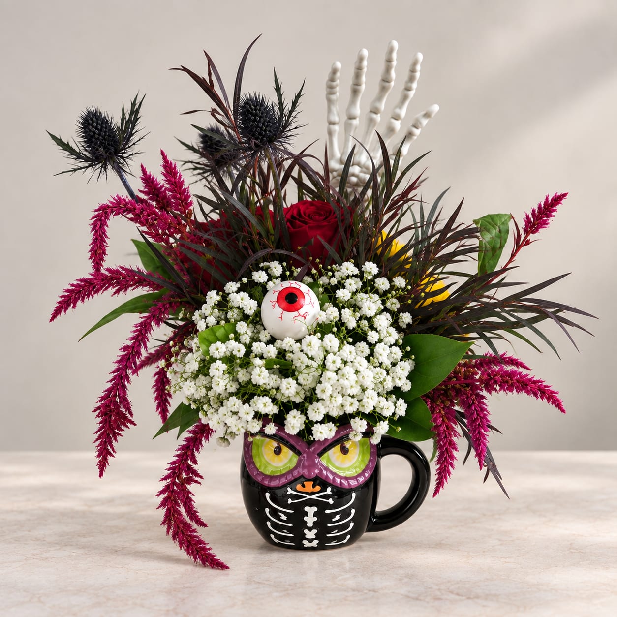 Halloween floral arrangement in a black skeleton mug with an eyeball topper