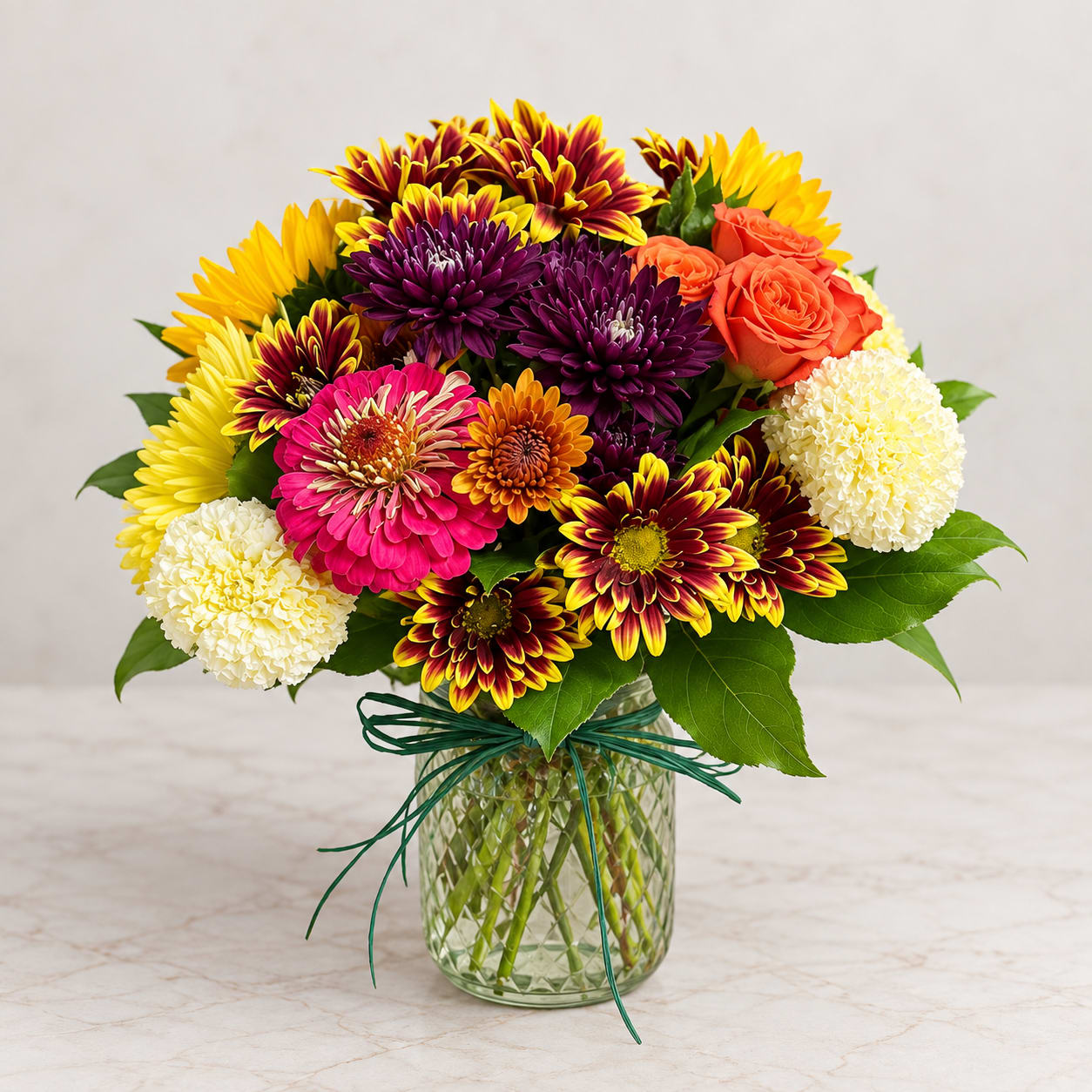 Colorful mixed bouquet in a glass vase with chrysanthemums, roses, and carnations