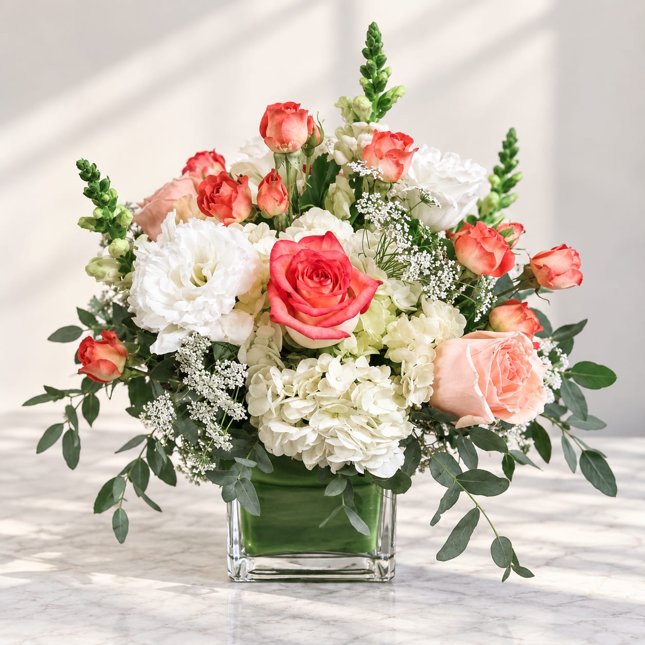 Mixed bouquet of pink and white roses in a clear square vase