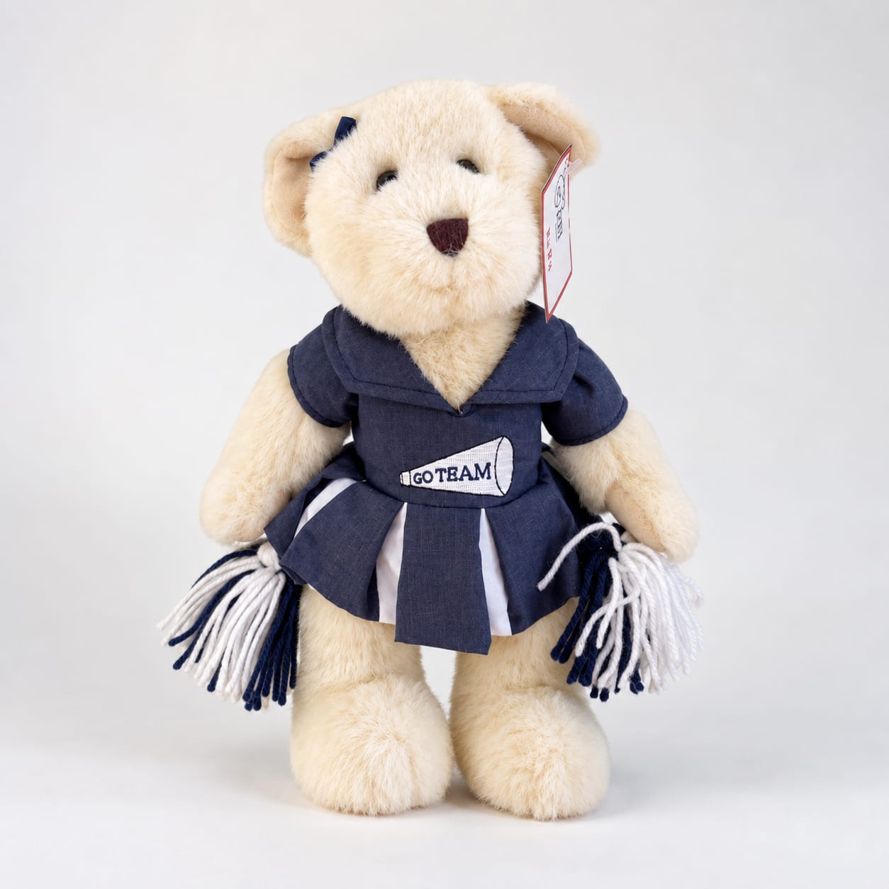 Plush teddy bear in a navy cheerleader outfit holding pom-poms