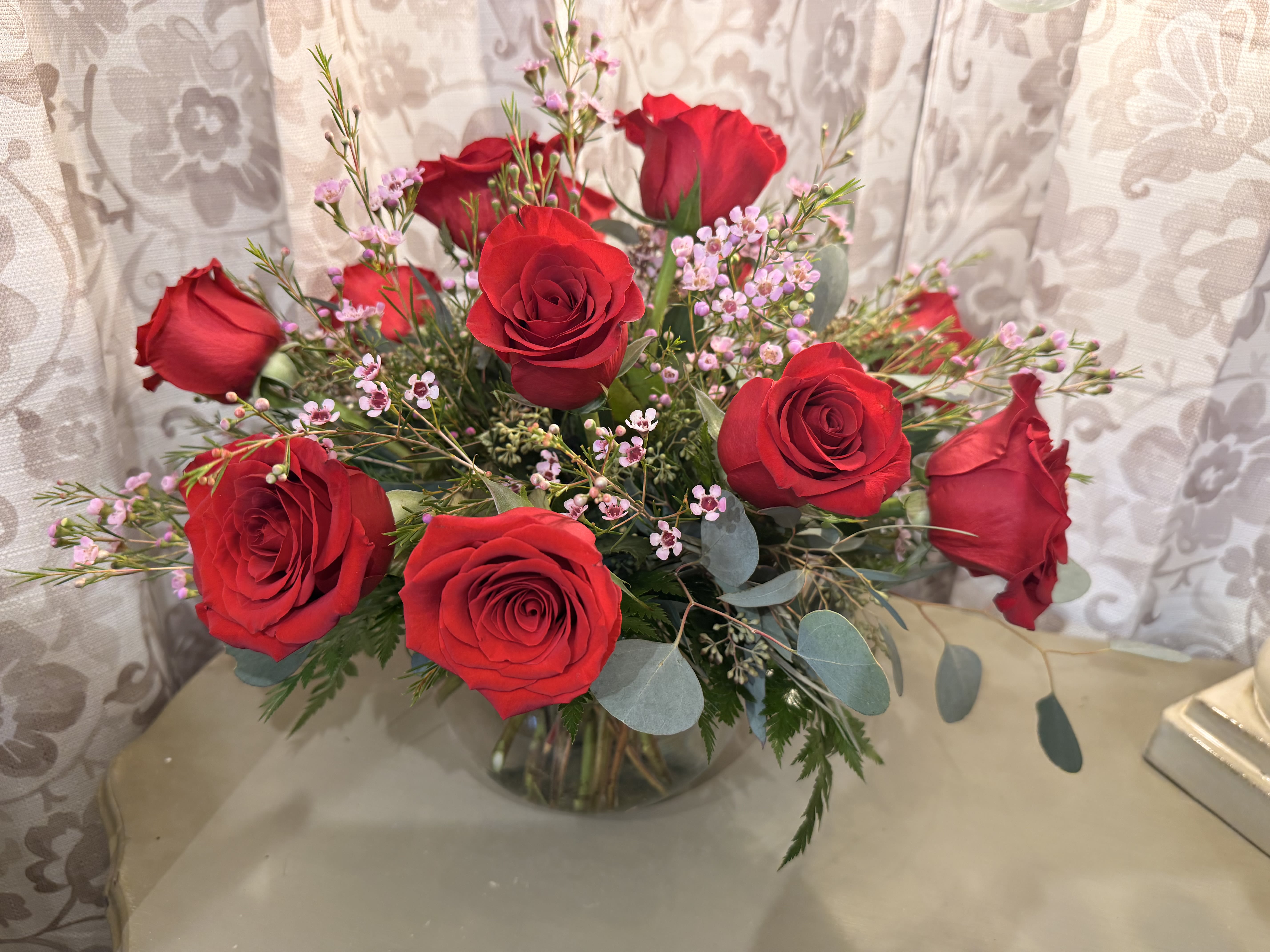 Bouquet of red roses with pink filler flowers in a glass vase