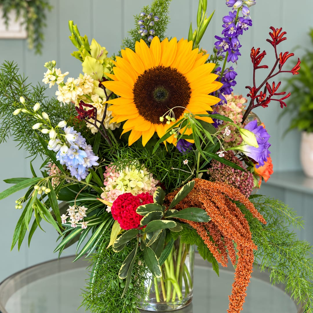 Colorful mixed bouquet with a large sunflower in a clear glass vase