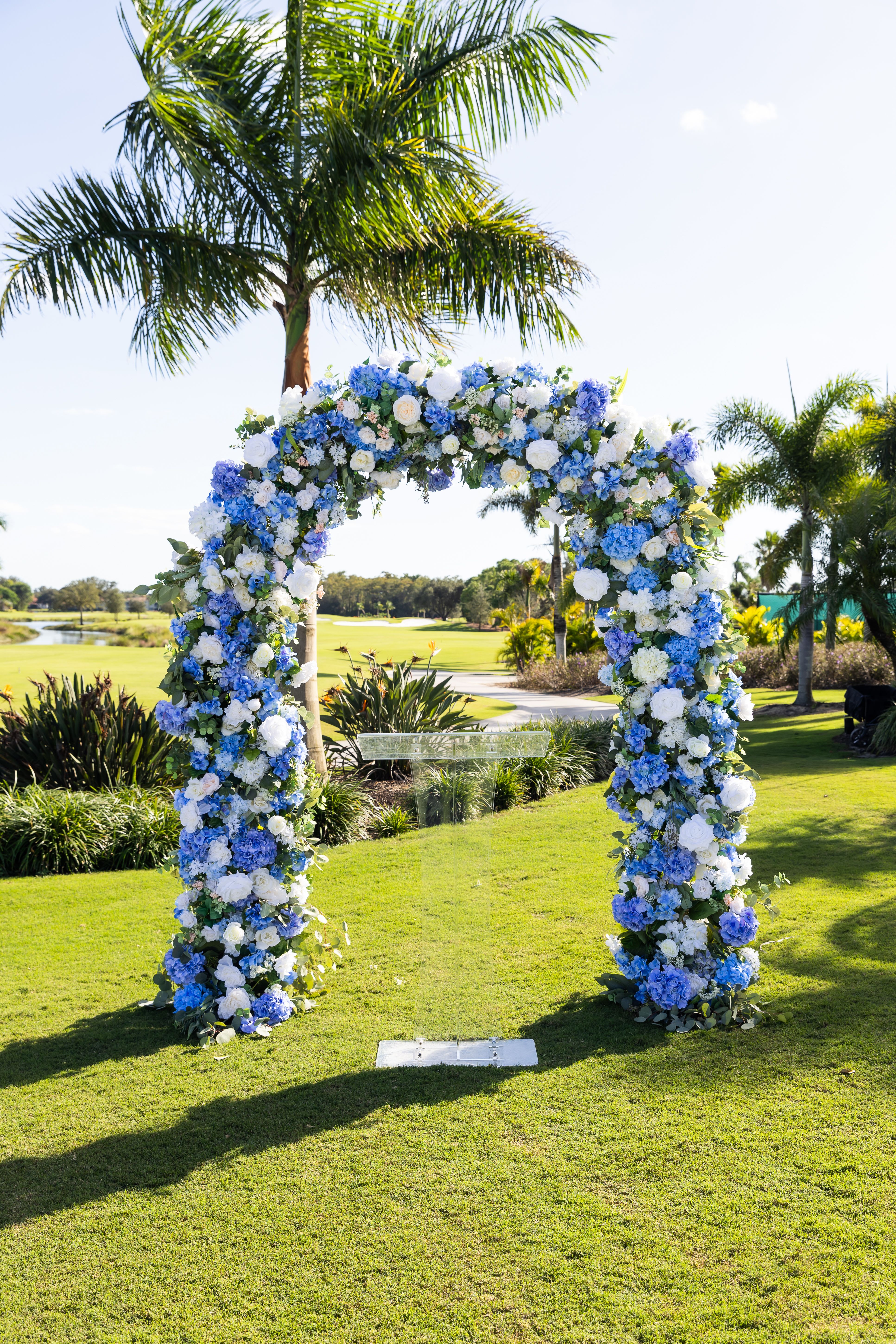 Blue and white floral arch on a lawn outdoors