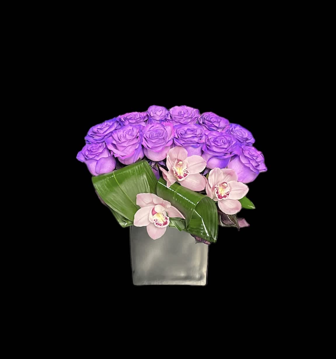 Modern cube vase with purple roses and pale pink orchids on a black background