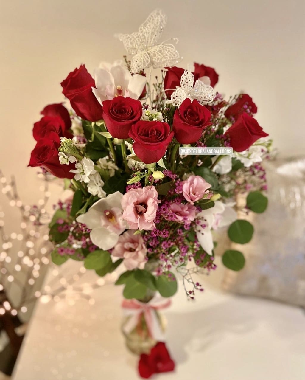 Bouquet of red roses and pink flowers with white butterfly accents