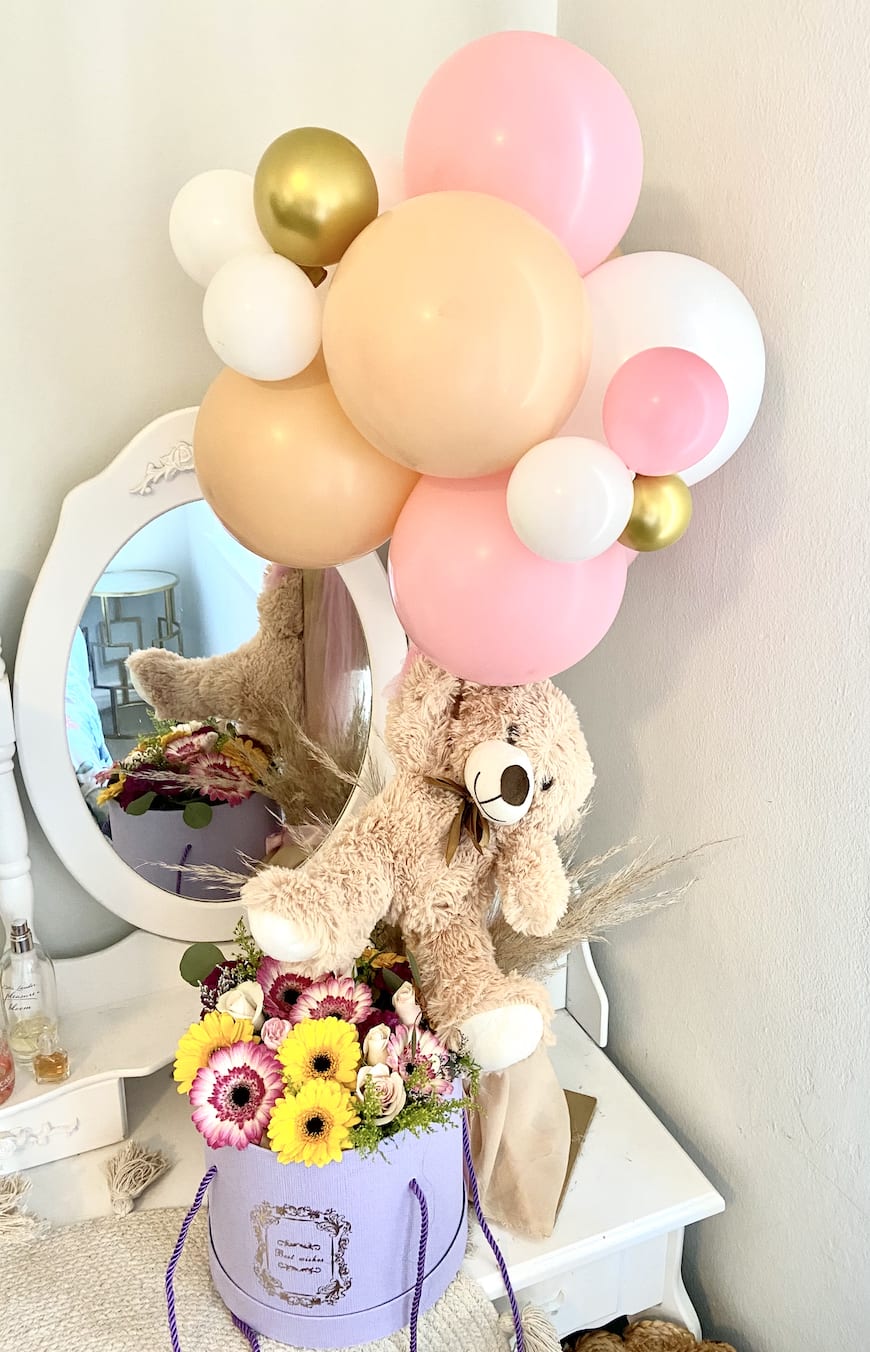 Teddy bear with pastel balloons and a flower box arrangement