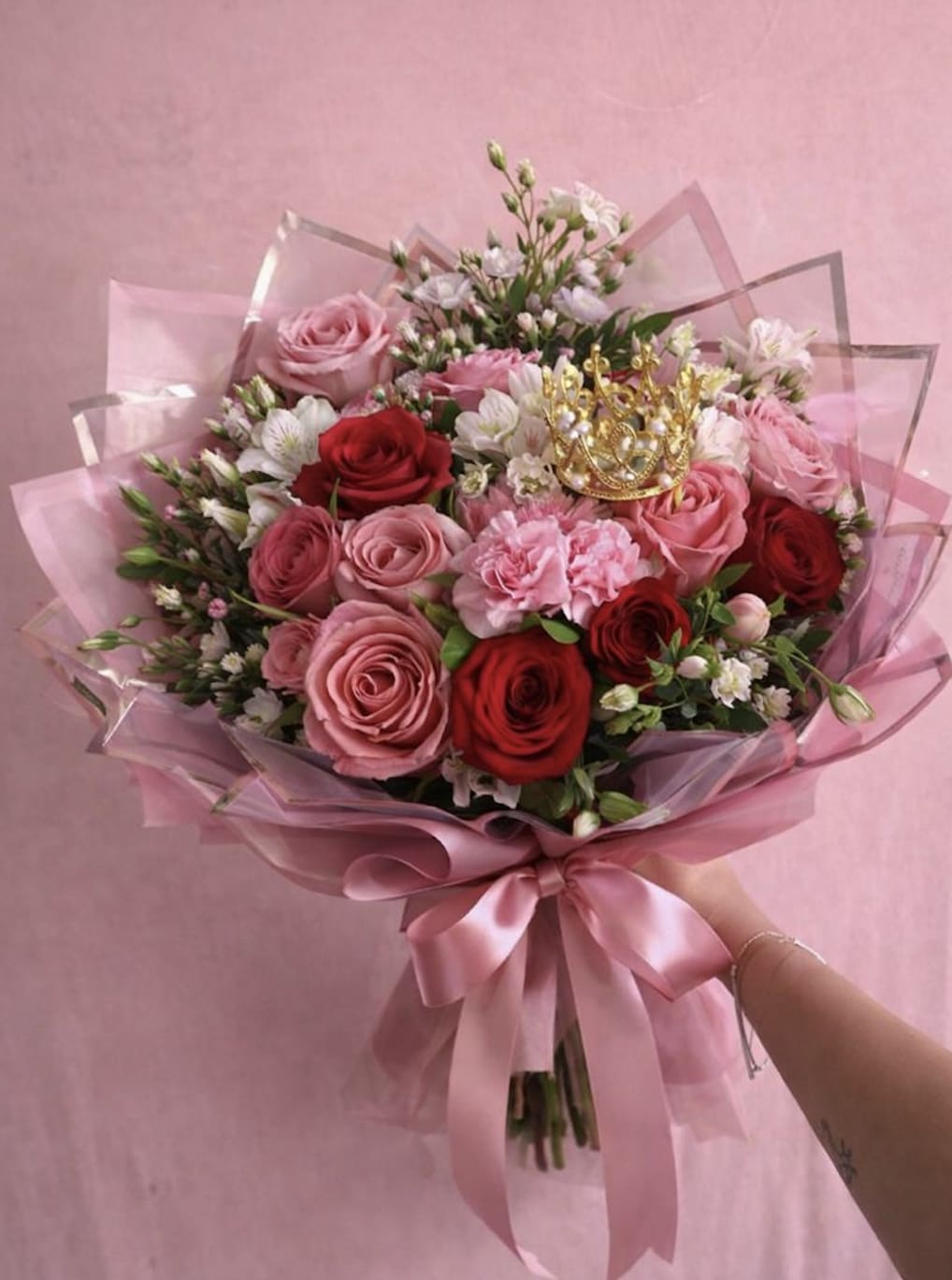 Pink and red rose bouquet wrapped in pink paper with a satin ribbon