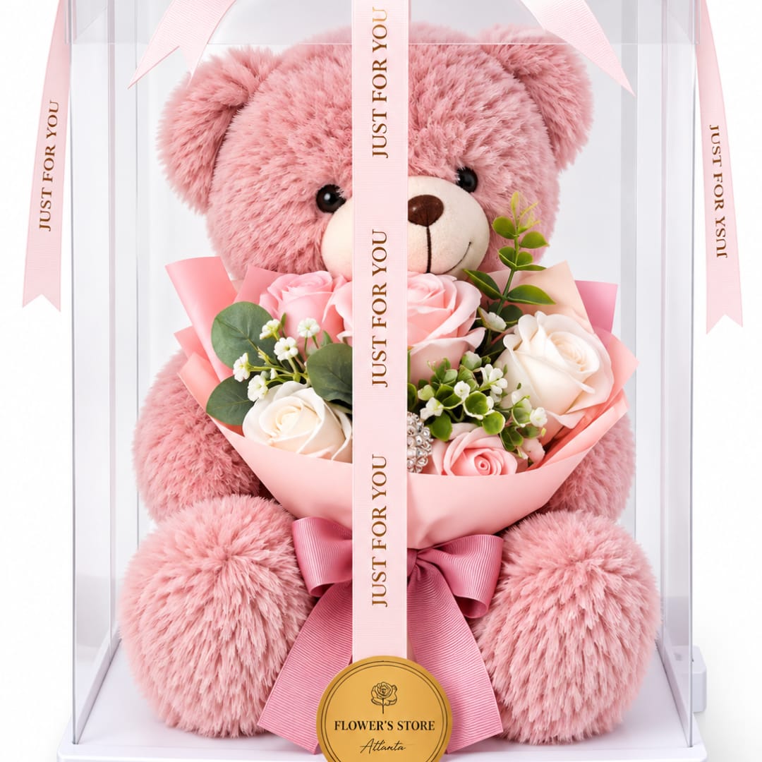 Pink teddy bear holding a bouquet of pink and white roses in a clear gift box