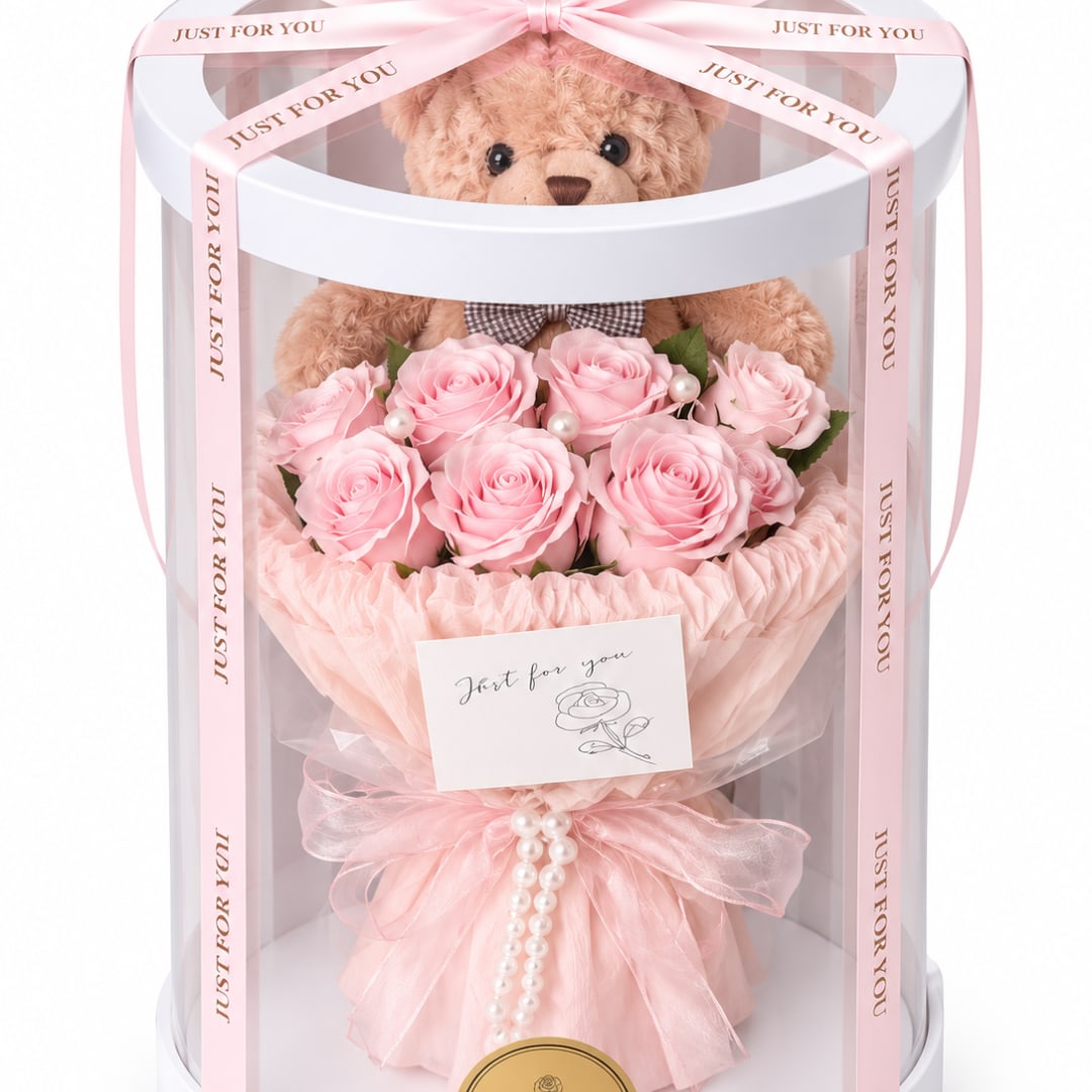 Pink rose bouquet in a clear gift box with a teddy bear and ribbon