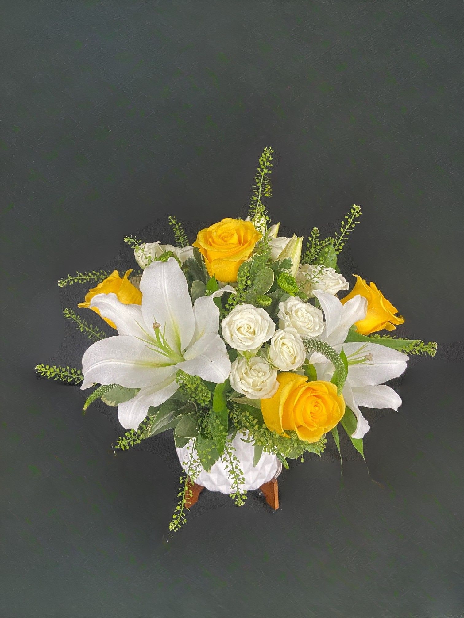 White lilies and yellow roses arranged in a white vase