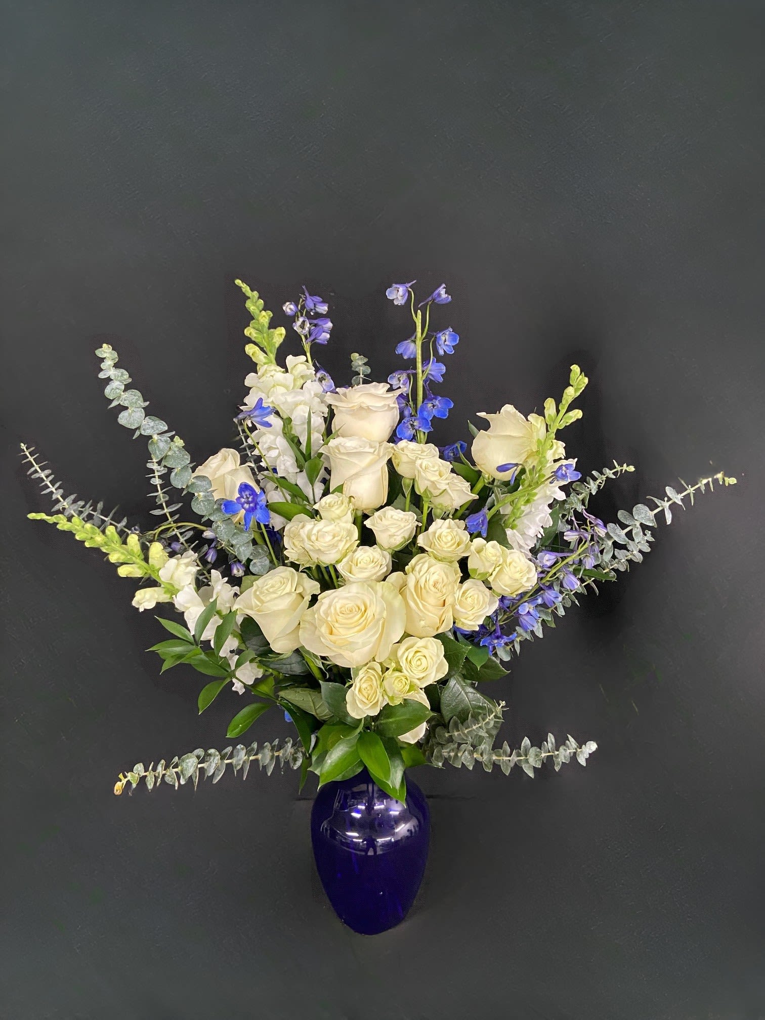 Orion's Belt - A blue and white arrangement featuring roses, spray roses, snapdragons and delphinium. Send this arrangement to anybody who likes stargazing or the night sky. A perfect gift to send for Hanukkah or the winter season.
