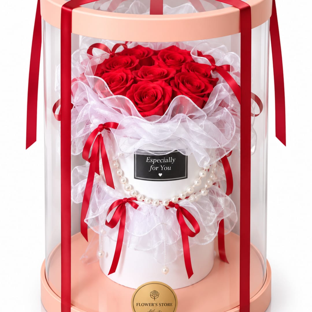 Red roses arranged in a white gift box with ribbons and a clear dome cover.