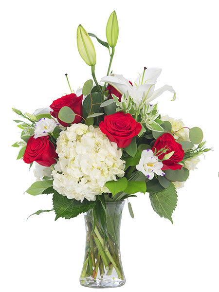 Bouquet of red roses, white lilies, and hydrangea in a glass vase