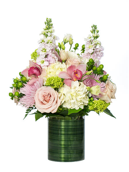 Arrangement of soft pink roses, orchids, and white hydrangeas in a green cylinder vase