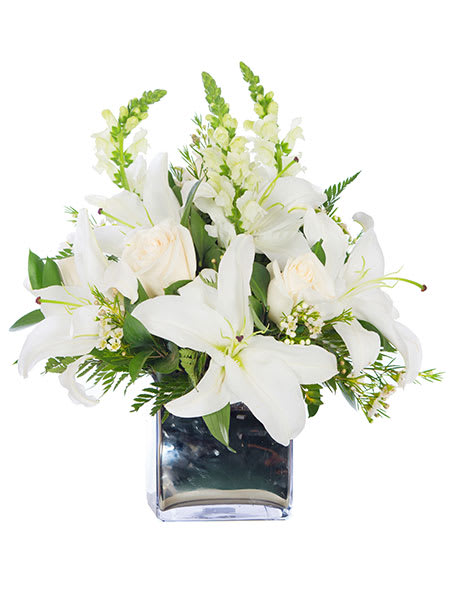 White lilies, roses, and snapdragons arranged in a silver cube vase