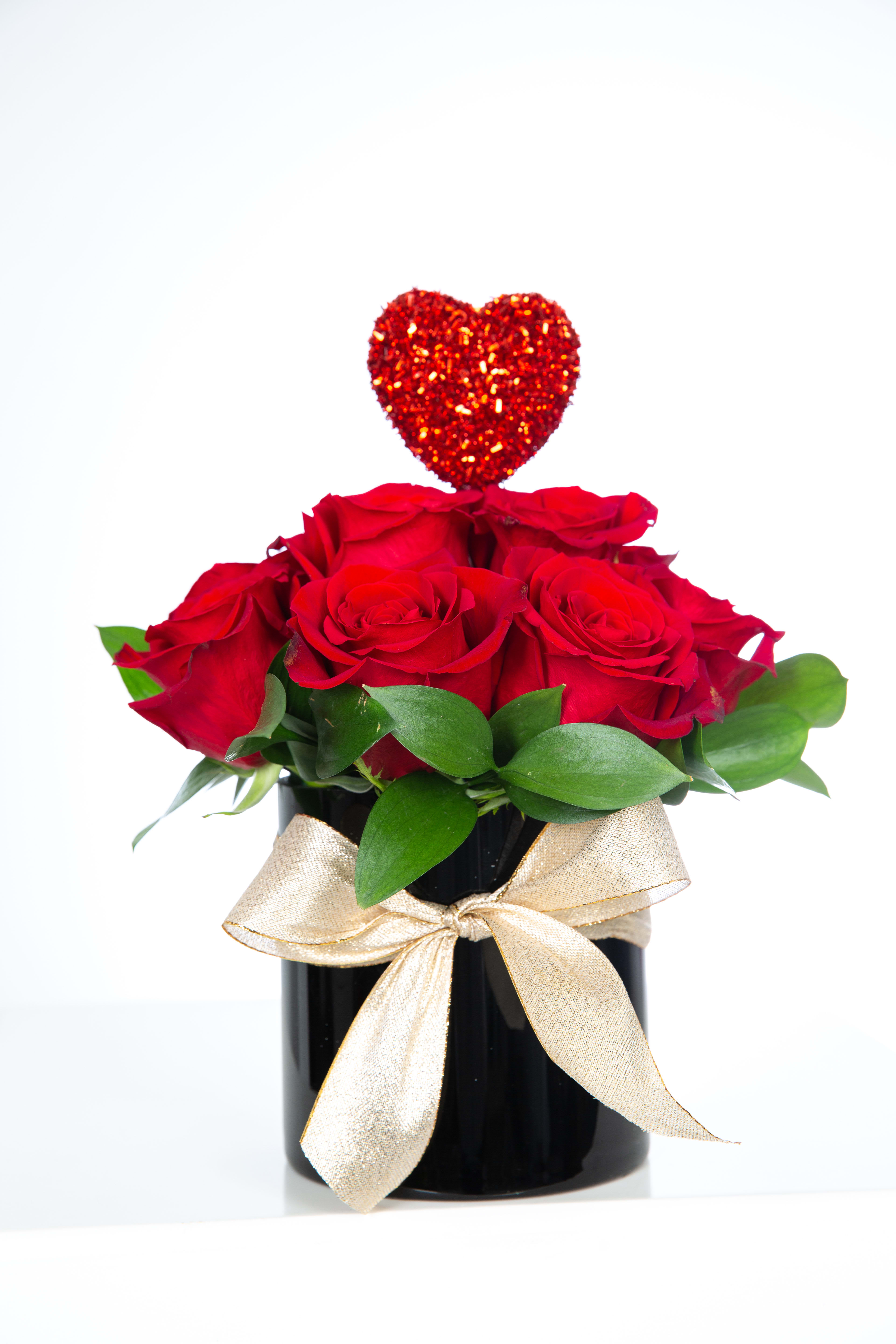 Red roses in a black vase with a glittery heart topper and gold ribbon