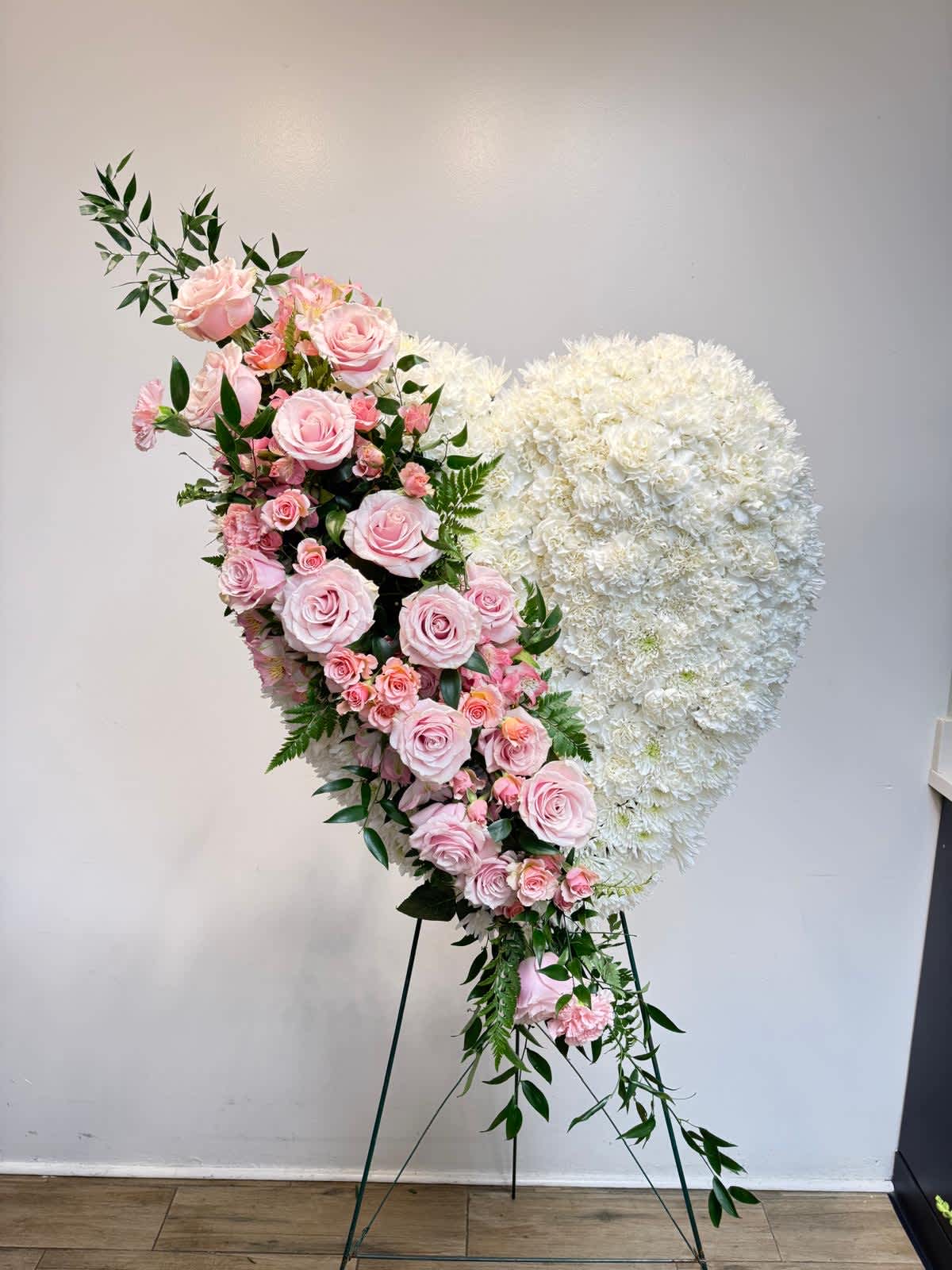 Heart-shaped floral arrangement with pink roses and white flowers on a stand