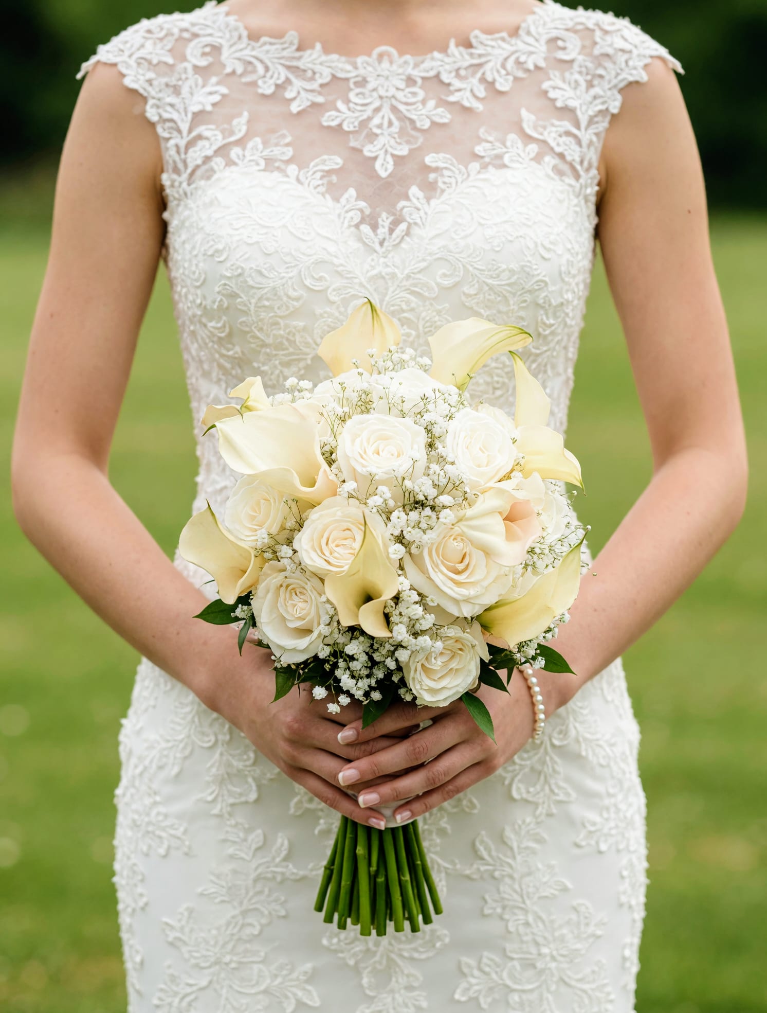 Bride holding a white bouquet with roses and calla lilies